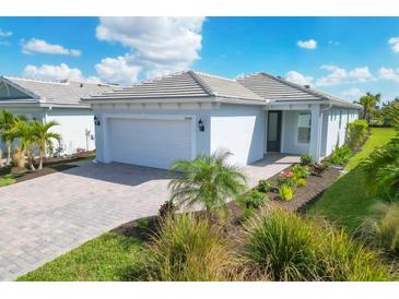 Single-story home with a white garage door and landscaping at 25544 Royal Tern Ln, Englewood, FL 34223