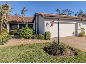 White condo with brown tile roof, landscaped lawn, and attached garage at 885 Country Club Cir # 61, Venice, FL 34293