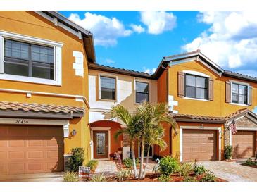 Orange townhome with two-car garage and landscaped front yard at 20428 Lagente Cir, Venice, FL 34293