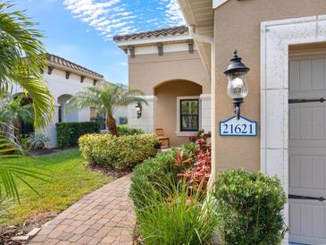 Inviting home exterior with a brick pathway, lush landscaping, and charming entryway at 21621 Winter Park Ct, Venice, FL 34293