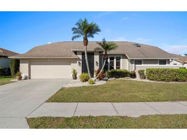 Tan house with palm trees, a large driveway, and well-maintained landscaping at 5003 Southern Pine Cir, Venice, FL 34293