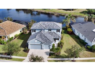 Two-story house with gray roof and light blue exterior, situated on a tree-lined street next to a lake at 21042 Anclote Ct, Venice, FL 34293