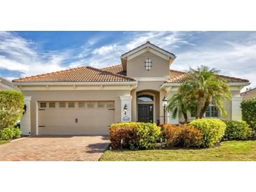 Tan house with brown roof, 2-car garage, and lush landscaping at 21208 Sandal Foot Dr, Venice, FL 34293