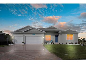 Two-car garage, light gray house, blue door, and landscaped lawn at 9401 President Cir, Port Charlotte, FL 33981