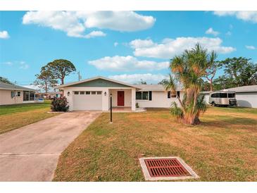 White single story home with red door, attached garage, and landscaped lawn at 872 Mohawk Rd, Venice, FL 34293