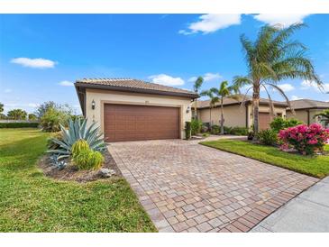 Charming single-Gathering home featuring a brick driveway, lush landscaping, and a two-car garage at 12837 Oriago St, Venice, FL 34293