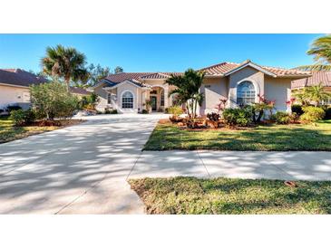 One-story home with tile roof, driveway, landscaping, and palm trees at 5039 Bella Terra Dr, Venice, FL 34293