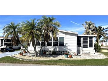 White single-wide home with palm trees, landscaped yard, and screened porch at 536 Amberjack Dr, North Port, FL 34287