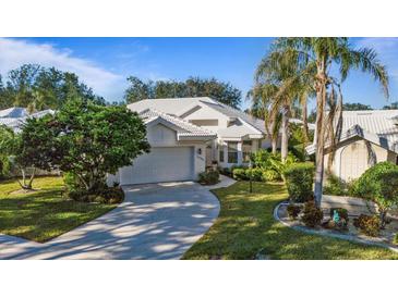 White house with tile roof, driveway, and palm trees in a sunny neighborhood at 1009 Harbor Town Dr, Venice, FL 34292