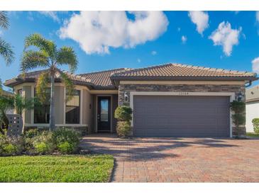Single-story home with stone accents, tile roof, and two-car garage at 13164 Rinella St, Venice, FL 34293