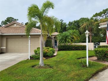 Single-story home with attached garage, palm trees, and manicured lawn at 201 Auburn Woods Cir, Venice, FL 34292