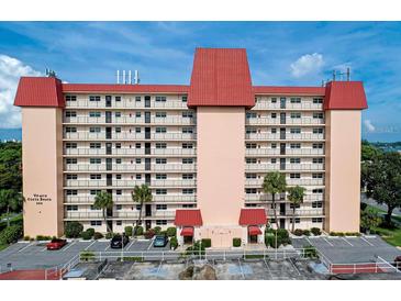 Front view of a multi-story building with red roof and ample parking at 232 Saint Augustine Ave # 704, Venice, FL 34285