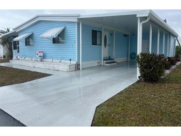 Charming blue single-story home featuring awnings, a covered entrance, and a well-maintained yard at 356 Longwood Dr, Venice, FL 34285