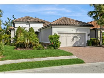 Single-story home with a tile roof, landscaped yard, and two-car garage at 5592 Semolino St, Nokomis, FL 34275
