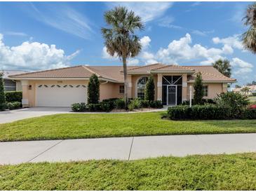 Tan house with tile roof, palm trees, and landscaped yard at 1579 Waterford Dr, Venice, FL 34292