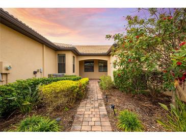 Brick walkway leads to charming villa entrance, surrounded by lush landscaping at 18891 Lanuvio St, Venice, FL 34293