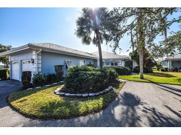 Bright blue house with attached garage and lush landscaping at 450 Wexford Cir # 106, Venice, FL 34293