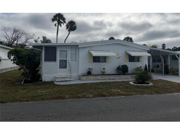 White single-wide manufactured home with carport and landscaping at 607 Cervina Dr, Venice, FL 34285