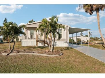 Tan mobile home with carport, wooden steps and palm trees at 6281 Oriole Blvd, Englewood, FL 34224