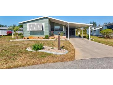 Mobile home with carport, landscaped yard, and paved driveway at 869 Cascade Ct, Englewood, FL 34223