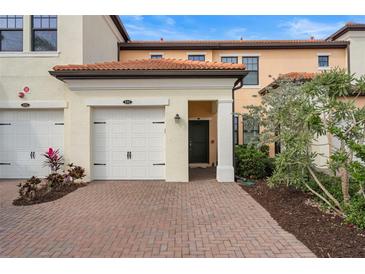 Inviting exterior featuring a two-car garage and well-manicured landscaping at 10058 Crooked Creek Dr # 201, Venice, FL 34293