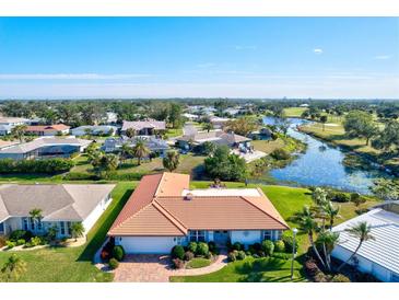 Aerial view showcasing a community of single-Gathering homes near a golf course and pond at 1008 Burning Oak Ct, Venice, FL 34293