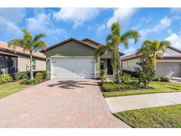 Single-story house with a two-car garage, landscaping and a brick driveway at 232 Teramo Way, Nokomis, FL 34275