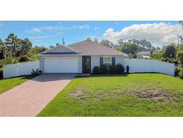 Newly constructed home with a white vinyl fence and a brick paver driveway at 5552 Guest Ter, Port Charlotte, FL 33981