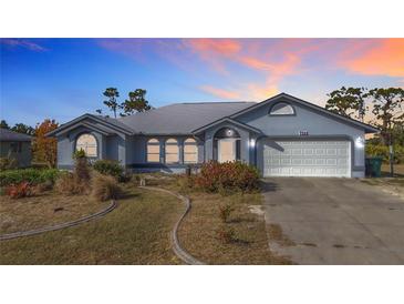 Charming single-story home featuring an attached two-car garage and a well-maintained, landscaped front yard at 7321 Teaberry St, Englewood, FL 34224
