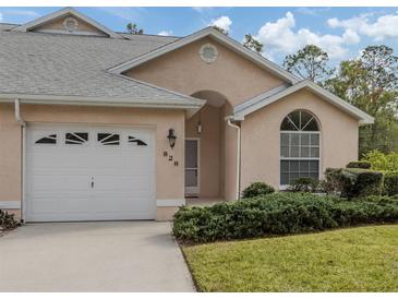 Tan stucco home with white garage door, landscaping, and arched entryway at 826 Bayport Cir, Venice, FL 34292