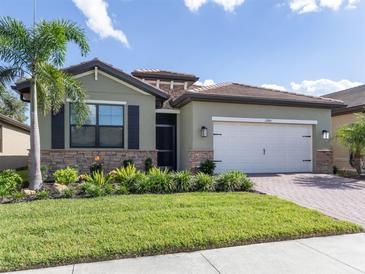 Single-story house with green exterior, landscaping, and a two-car garage at 11945 Lovegrass St, Venice, FL 34293