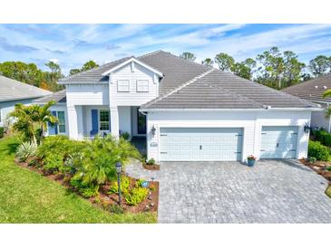 Two-story house with light gray roof, white walls, and light blue garage doors at 12460 Davie Ct, Venice, FL 34293