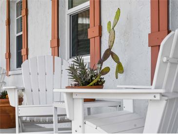 Inviting front porch with white chairs and potted plants at 1423 Avenida Del Circo # 1C, Venice, FL 34285