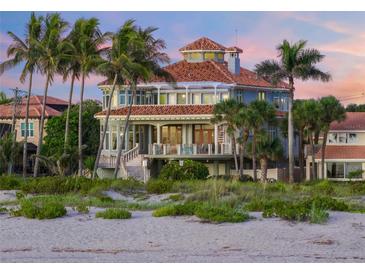 Beachfront home with palm trees, circular driveway, and stunning sunset views at 213 The Esplanade S, Venice, FL 34285