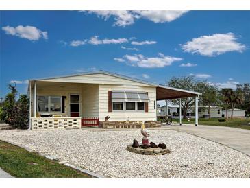 Single-wide mobile home with carport and landscaped yard at 3300 Blue Jay Ln, Englewood, FL 34224