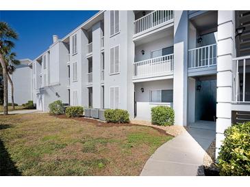 Exterior view of condo building, showing walkway, landscaping, and building facade at 408 Cerromar S Cir # 132, Venice, FL 34293