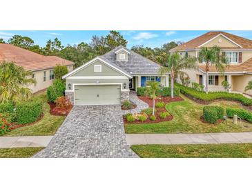 Single-story home with gray roof, light green walls, and a paver driveway at 12386 Sagewood Dr, Venice, FL 34293