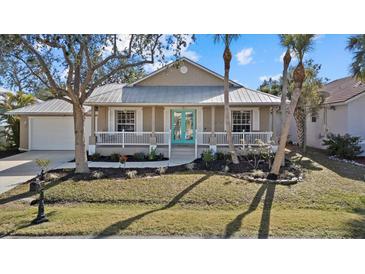 Tan house with teal front door, white porch, and landscaped yard at 205 Tortuga Dr, Nokomis, FL 34275