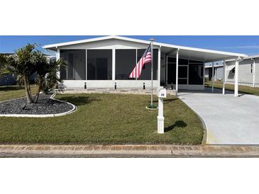 Single-wide mobile home with carport, screened porch, and landscaped yard at 28 Castaway Ct, North Port, FL 34287