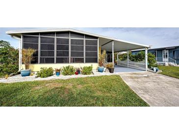 Yellow mobile home with covered porch, landscaped yard, and driveway at 3022 Audubon Ave, Englewood, FL 34224