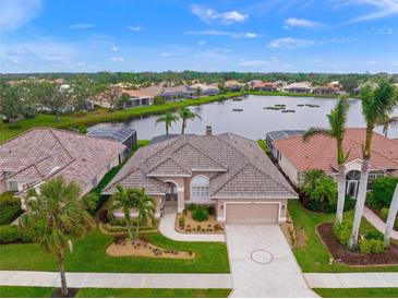 Aerial view of a beautiful home on a lake with lush landscaping at 430 Marsh Creek Rd, Venice, FL 34292