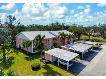 Aerial view of condo building with parking and lush landscaping at 458 Cerromar Rd # 483, Venice, FL 34293