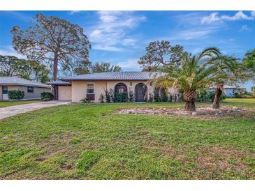 Tan single-story house with a palm tree and lush lawn at 519 Rubens Dr # 519, Nokomis, FL 34275