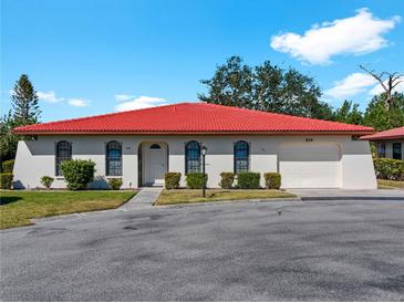 Single-story home with red tile roof, white walls, and well-manicured lawn at 854 Senda Plata # 22, Venice, FL 34293