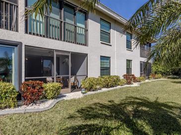 Ground-level condo showcasing a screened patio, manicured lawn, and lush landscaping at 936 Capri Isles Blvd # 102, Venice, FL 34292