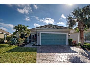 Single-story home with teal garage door, landscaping, and paver driveway at 19374 Rizzuto St, Venice, FL 34293