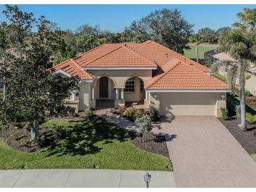 Tan one-story house with a tile roof, arched entryway, and landscaped yard at 298 Montelluna Dr, North Venice, FL 34275