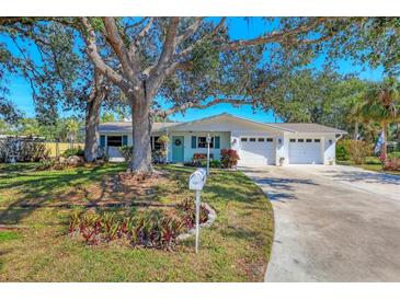 Charming home featuring a well-maintained front yard, mature tree, and a two-car garage, all under a sunny, clear sky at 3151 Datura Rd, Venice, FL 34293