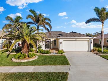 Single-story home with attached garage, landscaping, and palm trees at 4264 Wordsworth Way, Venice, FL 34293