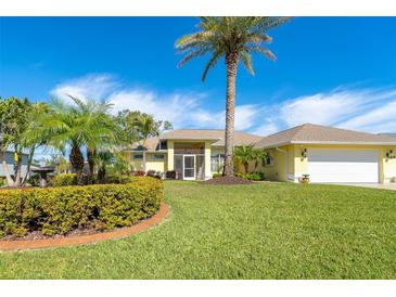 Bright yellow house with palm trees, lush landscaping, and a large driveway at 49 Perimeter Dr, Englewood, FL 34223